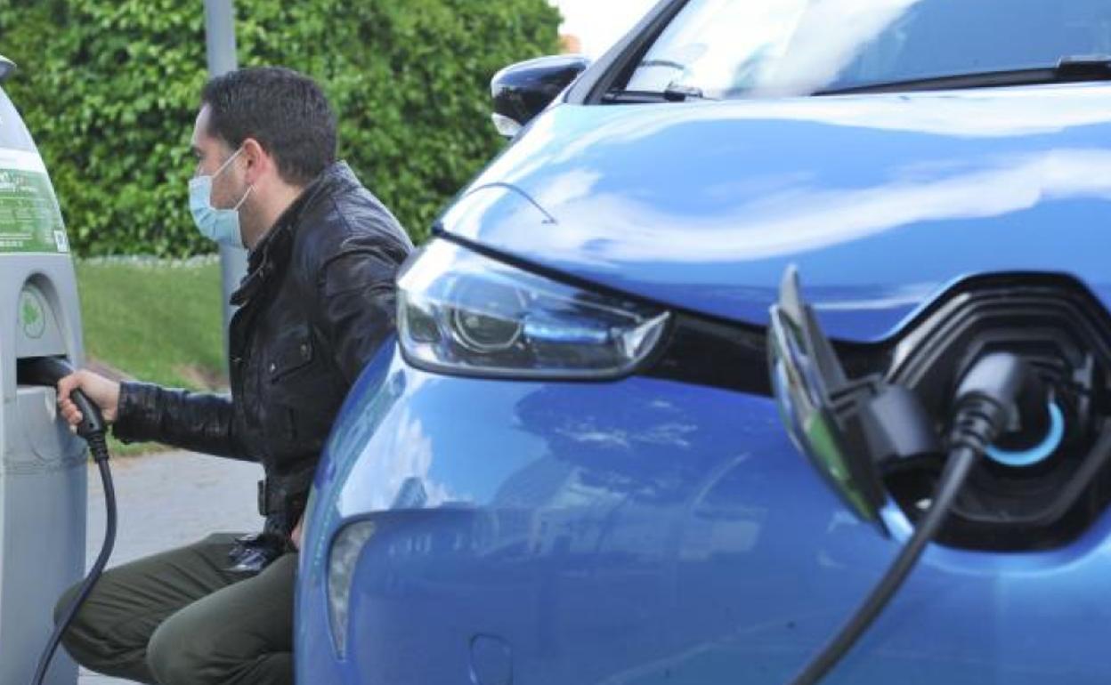 Un conductor enchufa su coche eléctrico.