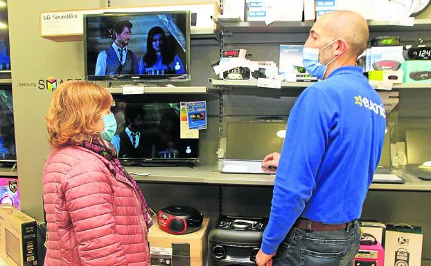 Un dependiente atiende a una mujer en una tienda de aparatos electrónicos. 