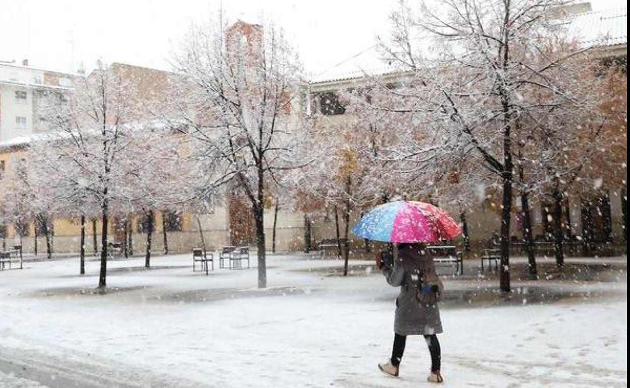 Una mujer pasea bajo la nieve por las calles de Palencia. 