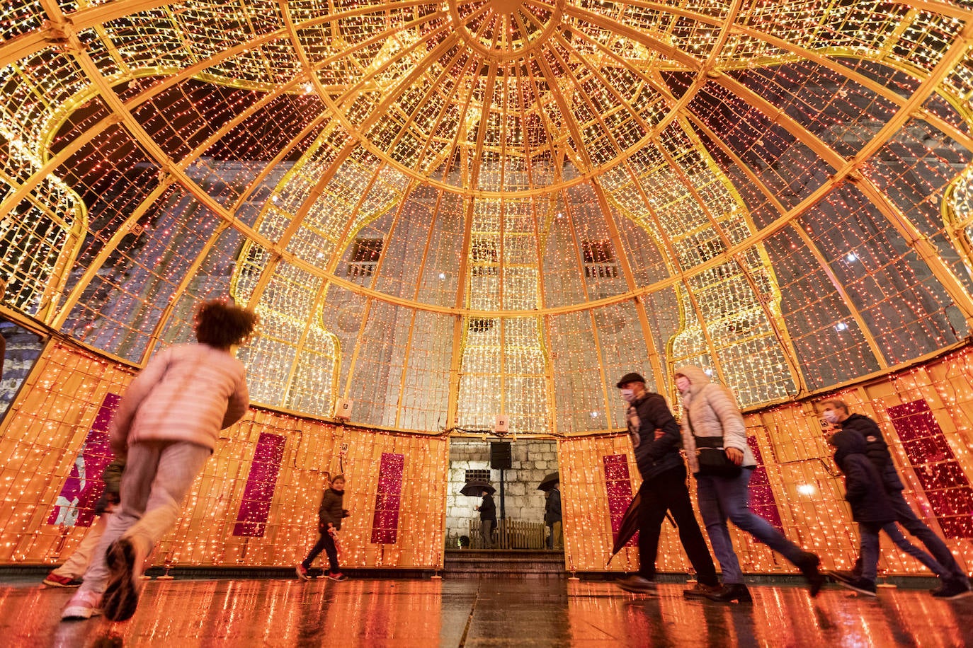 Varias personas, en el interior de una de las enormes coronas de los Reyes Magos instaladas en la plaza de Portugalete.