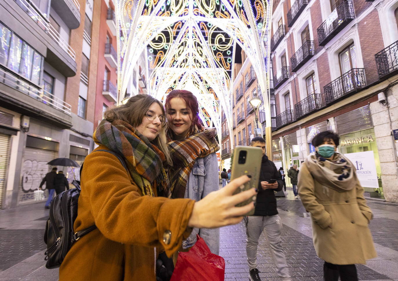 Dos jóvenes se hacen un selfie con las luces de la calle Santiago de fondo.