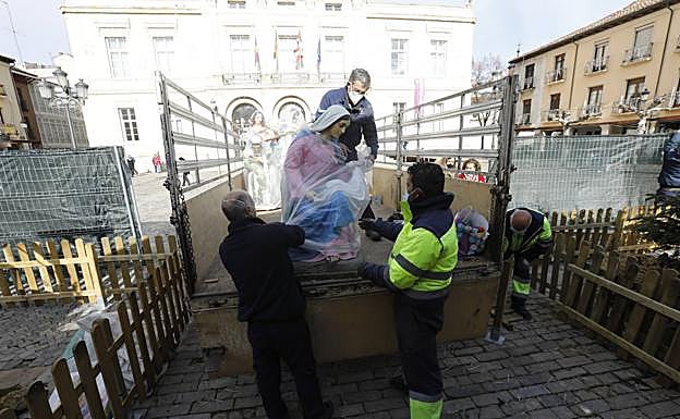 Los trabajadores del Ayuntamiento retiran el plástico de protección de la figura de la Virgen.