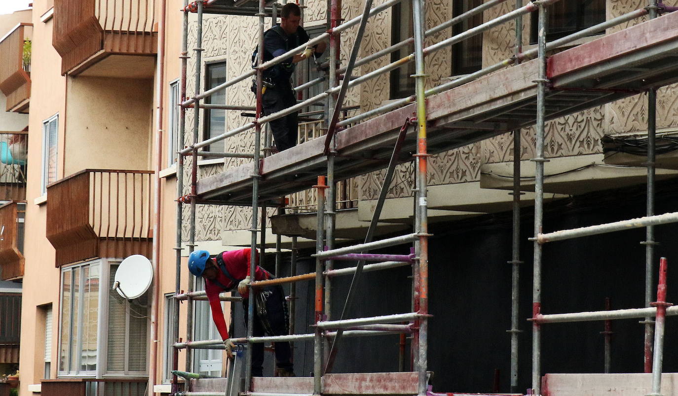 Dos obreros subidos a un andamio en la reforma de una vivienda en un barrio de la capital segoviana. 