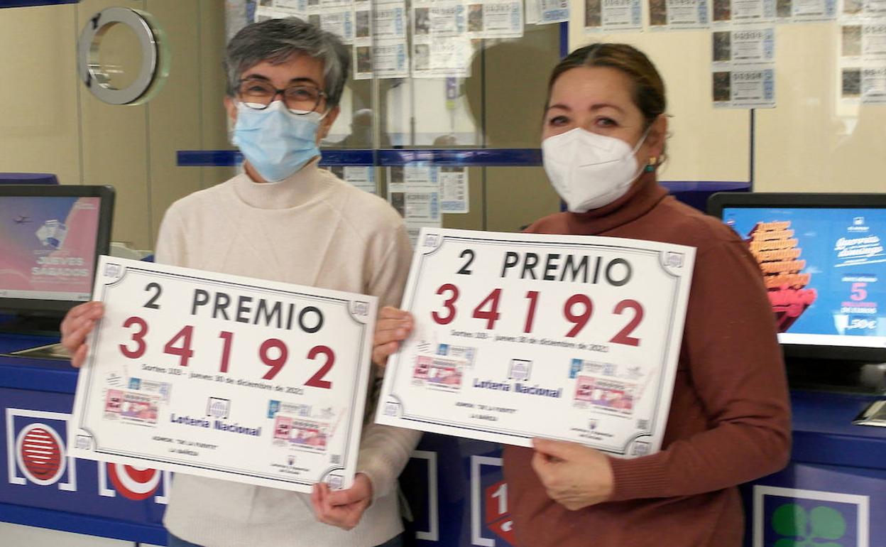 Dos de las loteras que llevaron la suerte a León posan con el número premiado. 