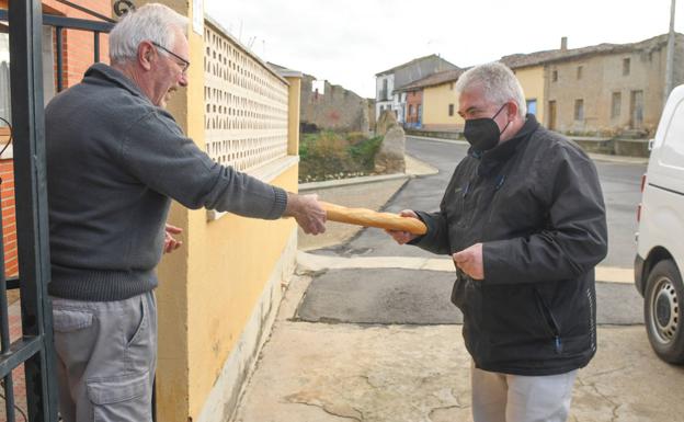 Jesús, panadero de Gallegos de Hornija, entrega una barra a un vecino.