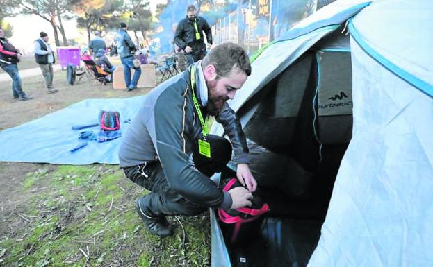 Un motero monta la tienda en la zona de acampada en el Pinar de Antequera