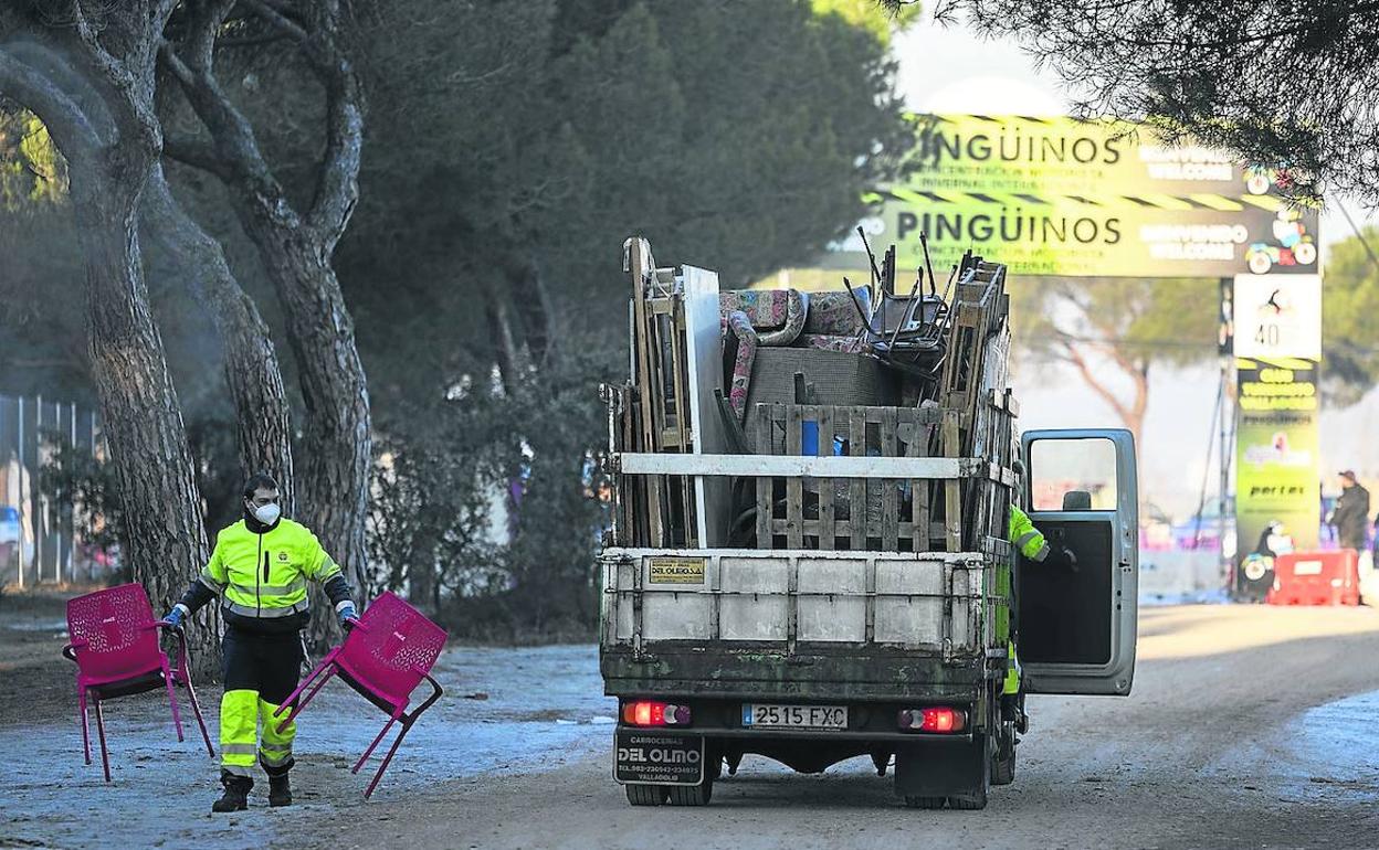 Un empleado de limpieza del Ayuntamiento recoge dos sillas para depositarlas en uno de los camiones de recogida de residuos