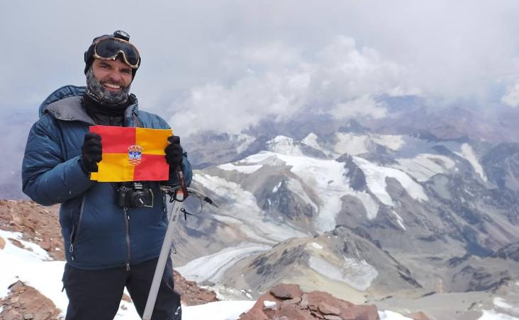 Rodrigo Zapatero posa con la bandera de Cisneros, su pueblo, en la montaña argentina.