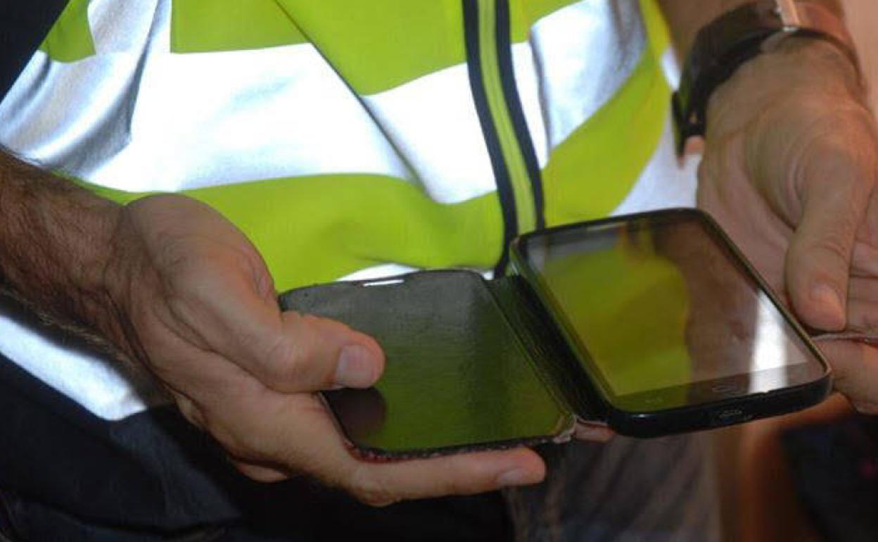 Imagen de archivo de un policía revisando un móvil incautado. 