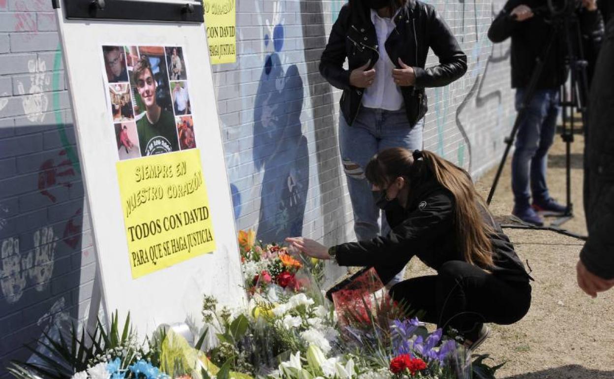 La madre de David coloca flores junto a la imagen de su hijo. 