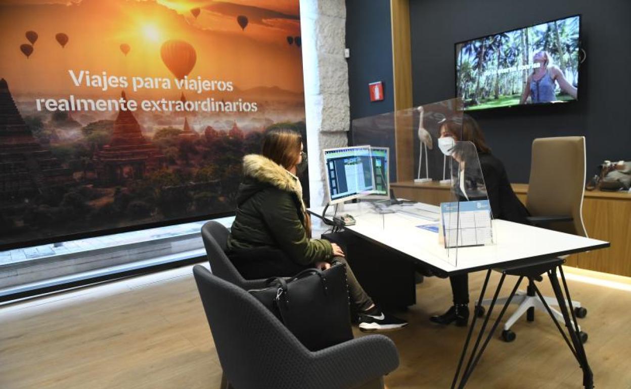 Una agente atiende a una cliente que pregunta por un viaje.