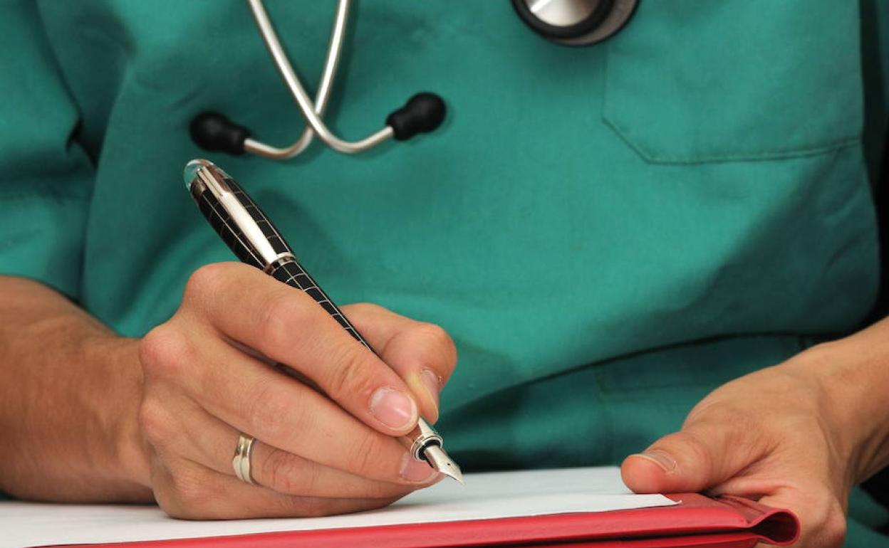 Una médico toma nota en la consulta. 