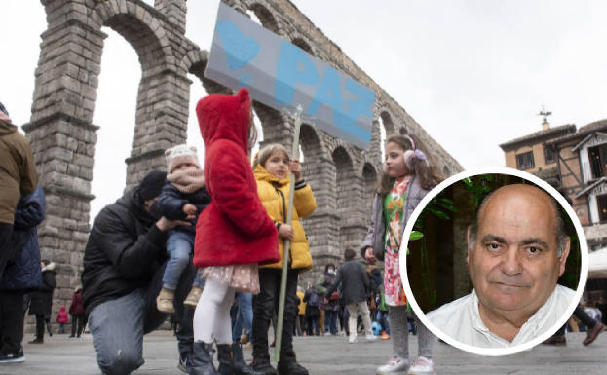 Unos niños sujetan un cartel por la paz en Ucrania en una concentración en Segovia, en el círculo, el que fuera párroco de El Espinar, Valentín Bravo. 