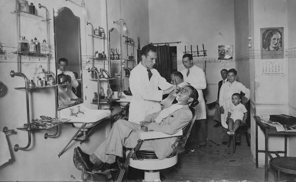 Lorenzo Ordóñez González (en primer término) trabajando en su barbería en agosto de 1933.