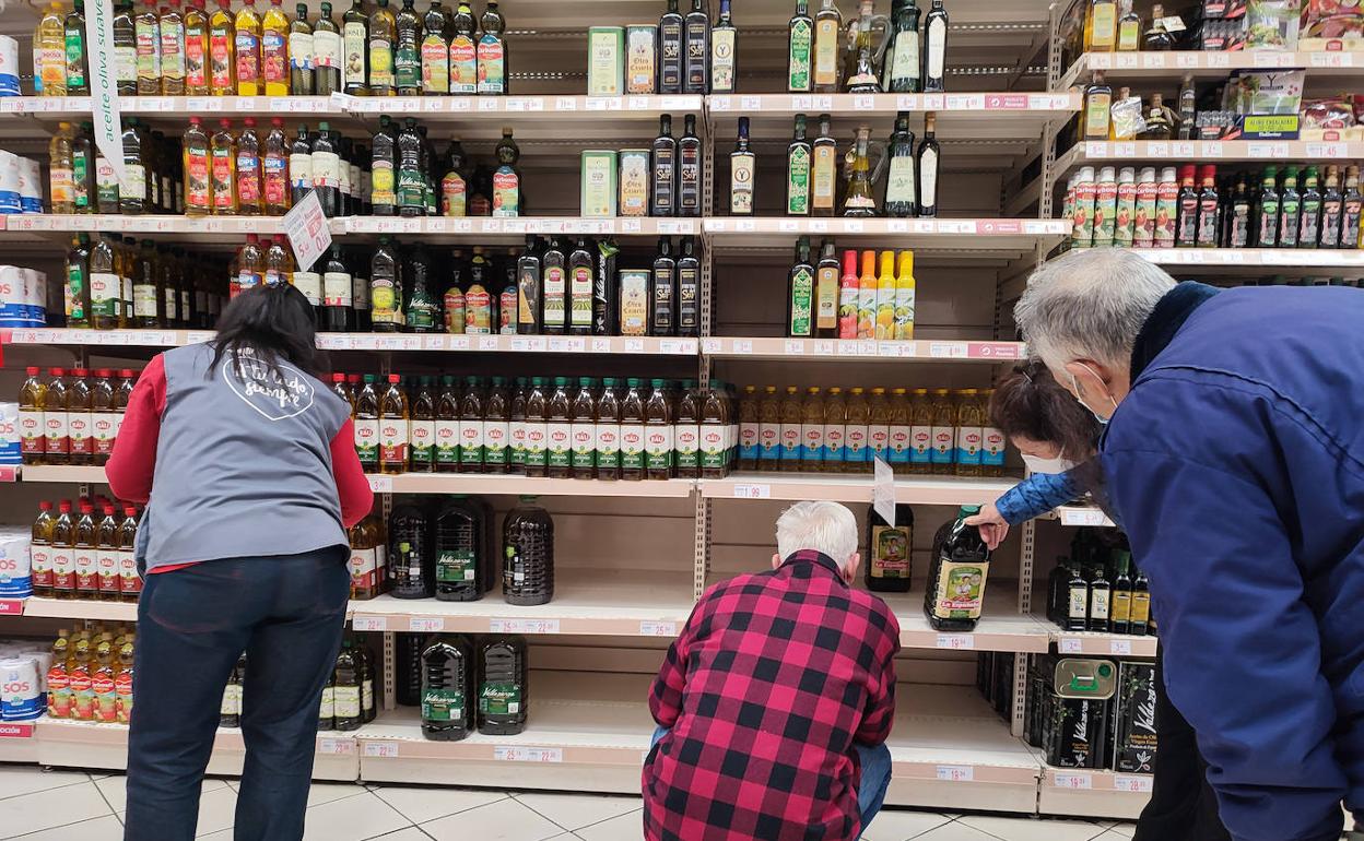 Varios clientes observan el stand del aceite en un supermercado. 