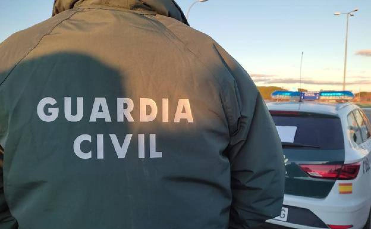 Un agente de la Guardia Civil detrás de un coche patrulla.