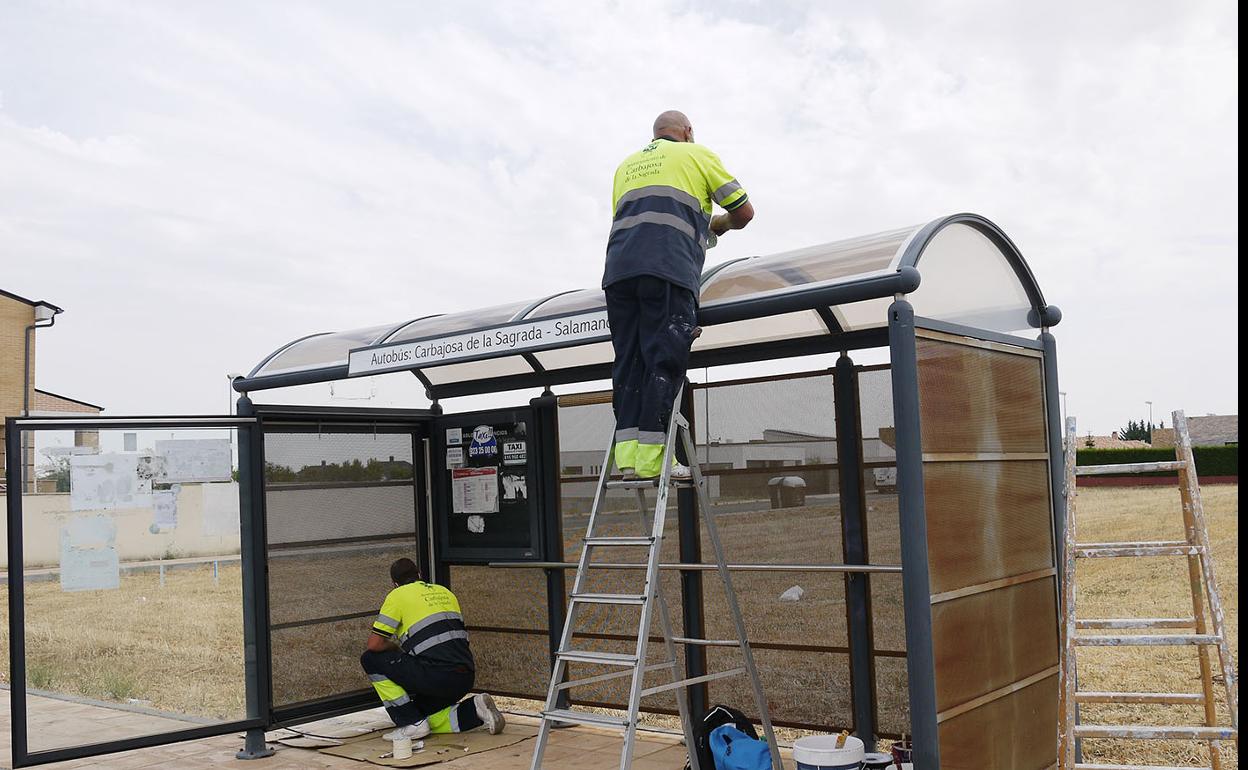 Empleados municipales pintando una marquesina. 