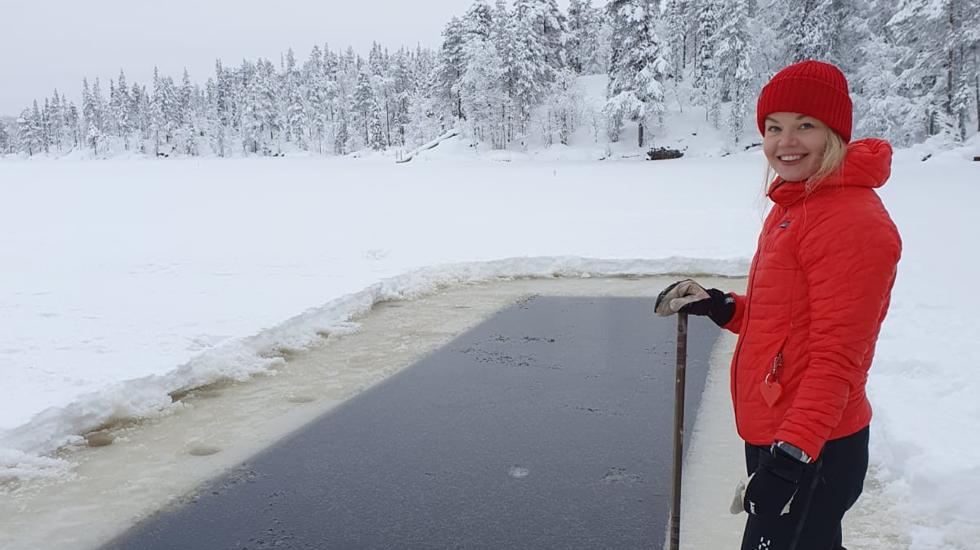 Elina posa junto a una 'piscina' natural de hielo abierta junto a un bosque nevado en la que se dispone a zambullirse.