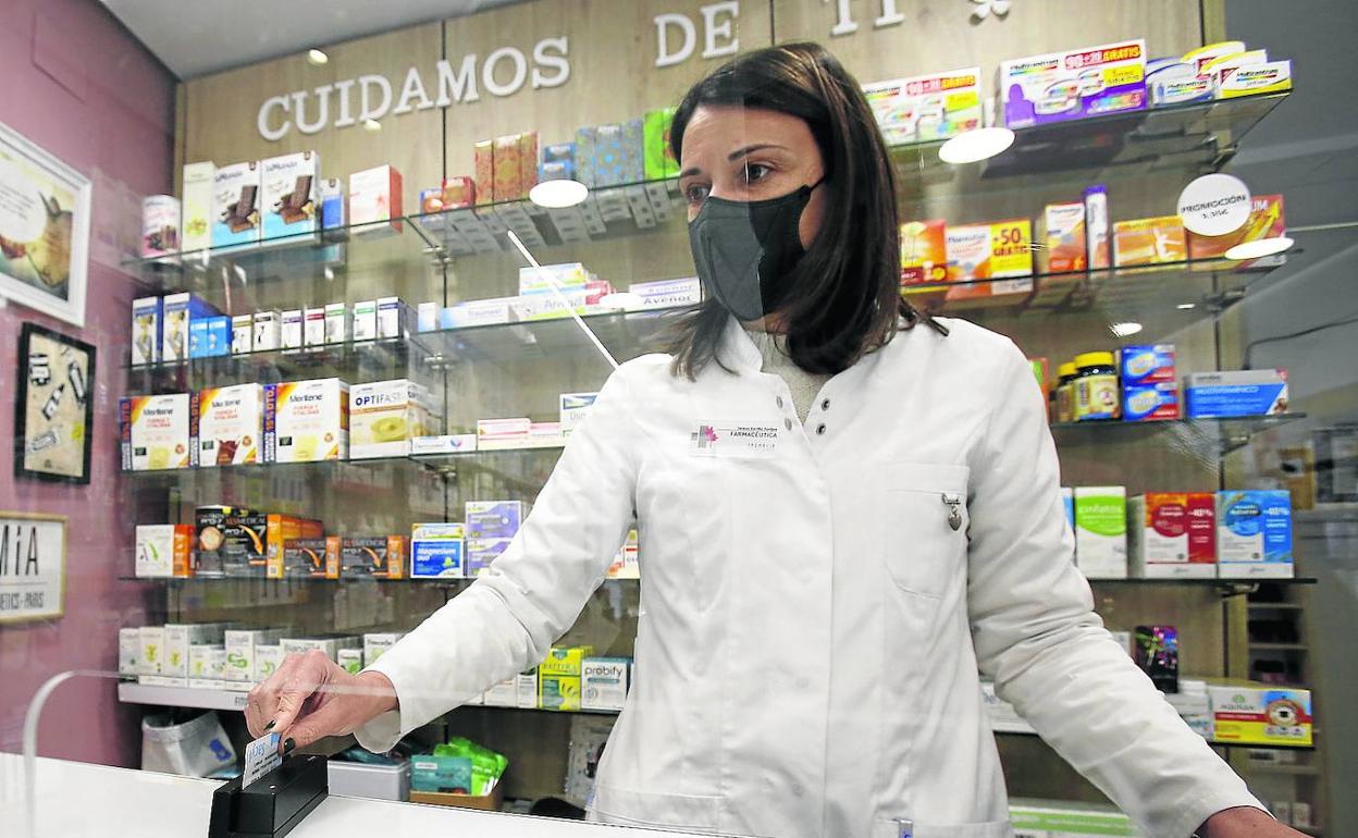 Una farmacéutica pasa la receta electrónica por el lector en una farmacia del centro de Palencia. 
