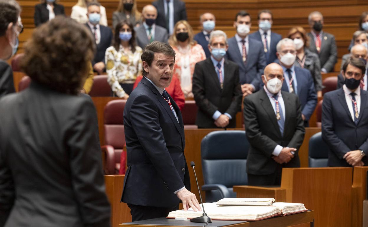 Mañueco se vuelve y mira a Ayuso (de espaldas).