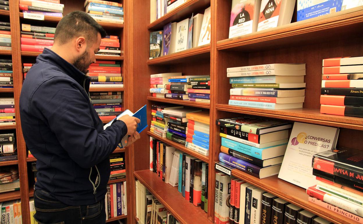 Un hombre hojea un libro en una librería de la capital segoviana. 
