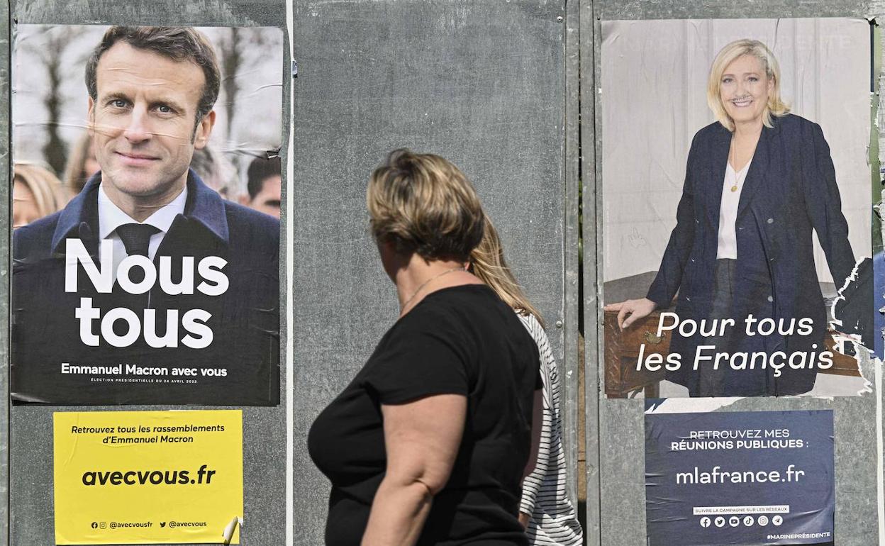 Dos mujeres pasean delante de sendos carteles de los canditatos presidenciales en Francia.