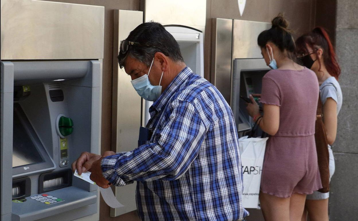 Varias personas sacan dinero de un cajero.