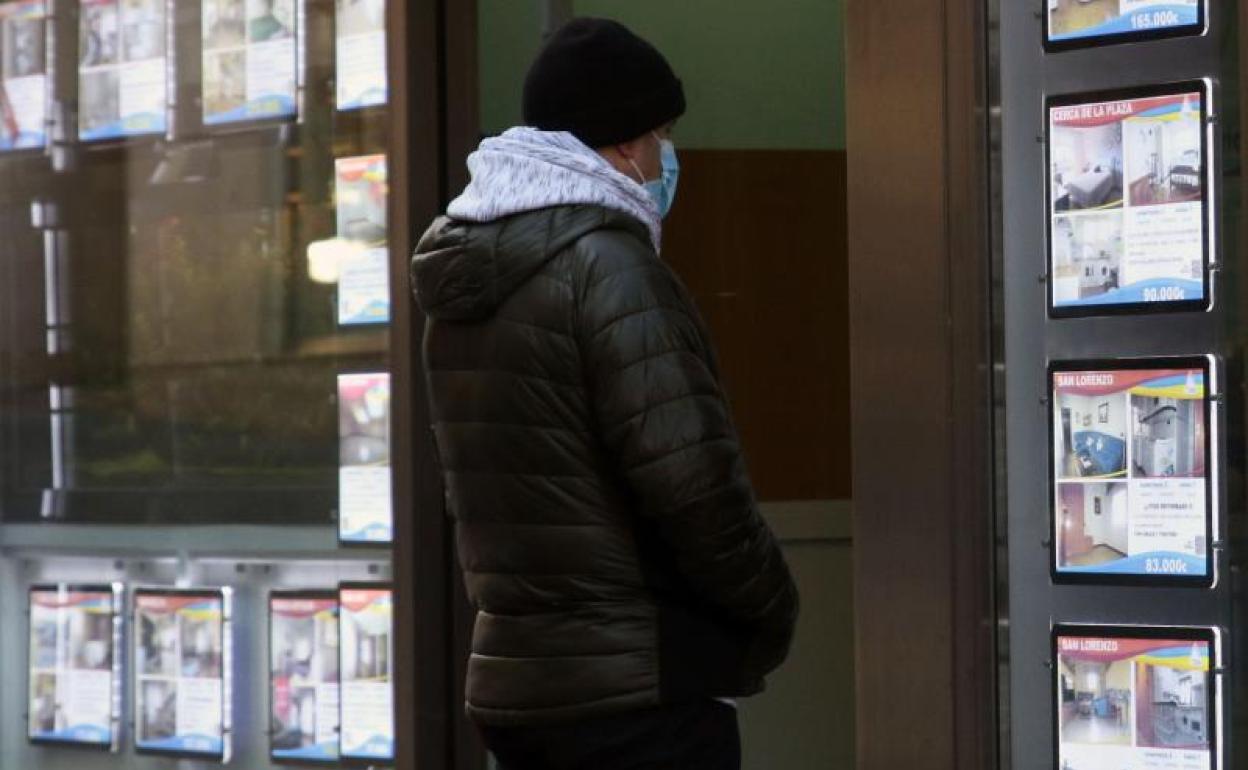 Un hombre examina pisos en venta en el escaparate de una inmobiliaria en Segovia.