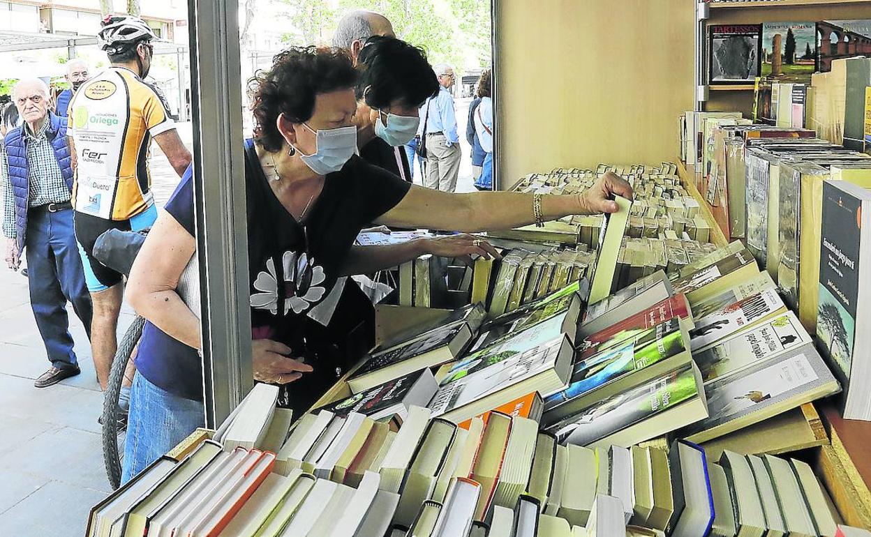 Dos mujeres buscan entre los ejemplares en una de las seis librerías de Castilla y León que forman parte de la Feria del Libro Antiguo en el Salón.