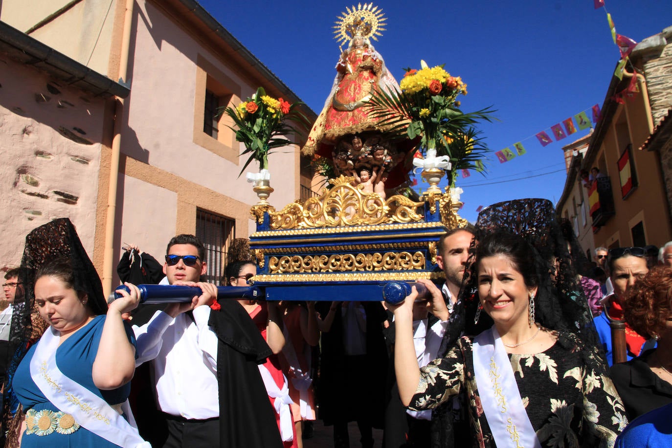 Los grupos de paloteo preceden el paso de la Virgen del Castillo por uno de los arcos de flores de papel en Bernardos. 