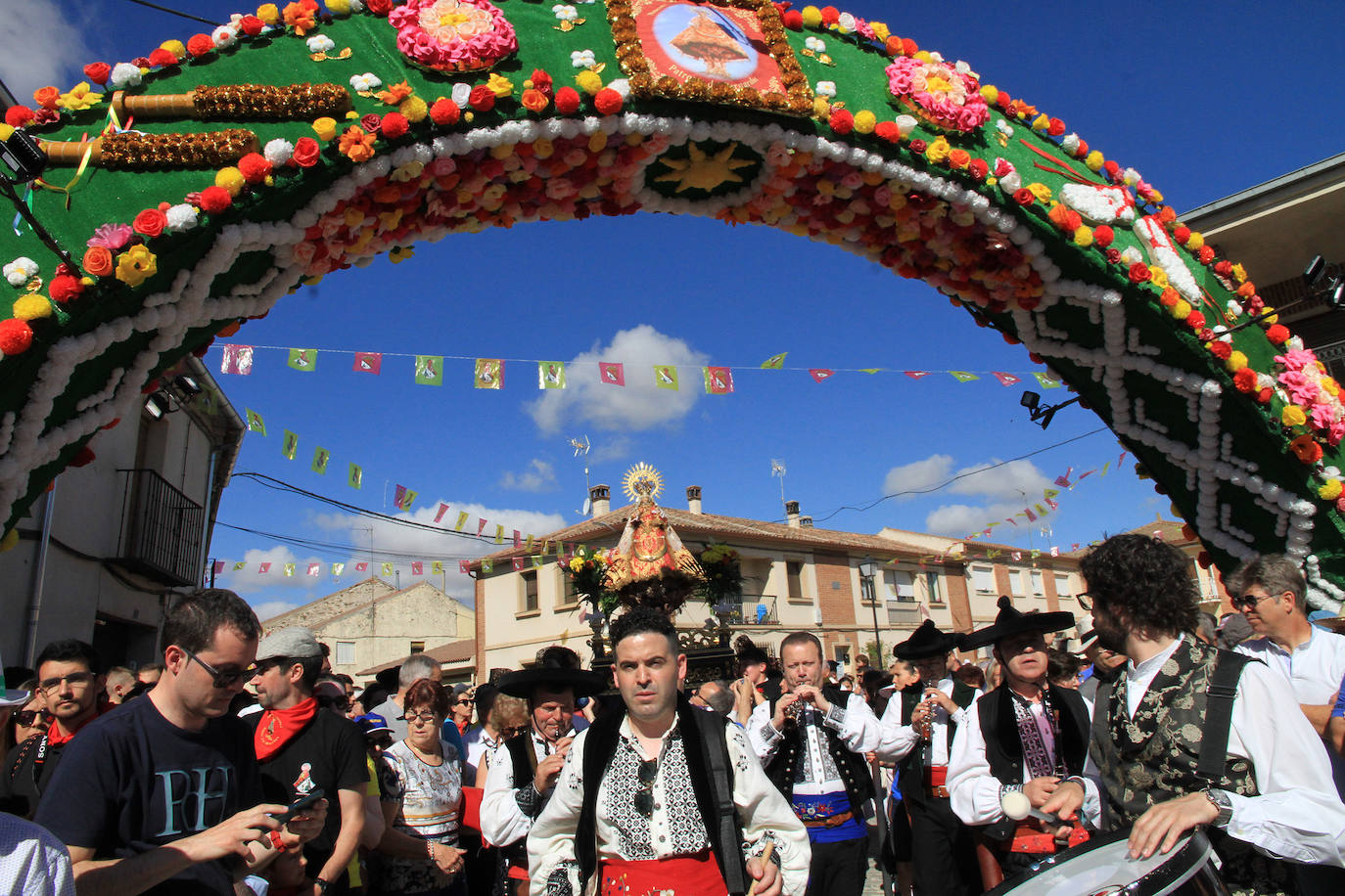 Los grupos de paloteo preceden el paso de la Virgen del Castillo por uno de los arcos de flores de papel en Bernardos. 