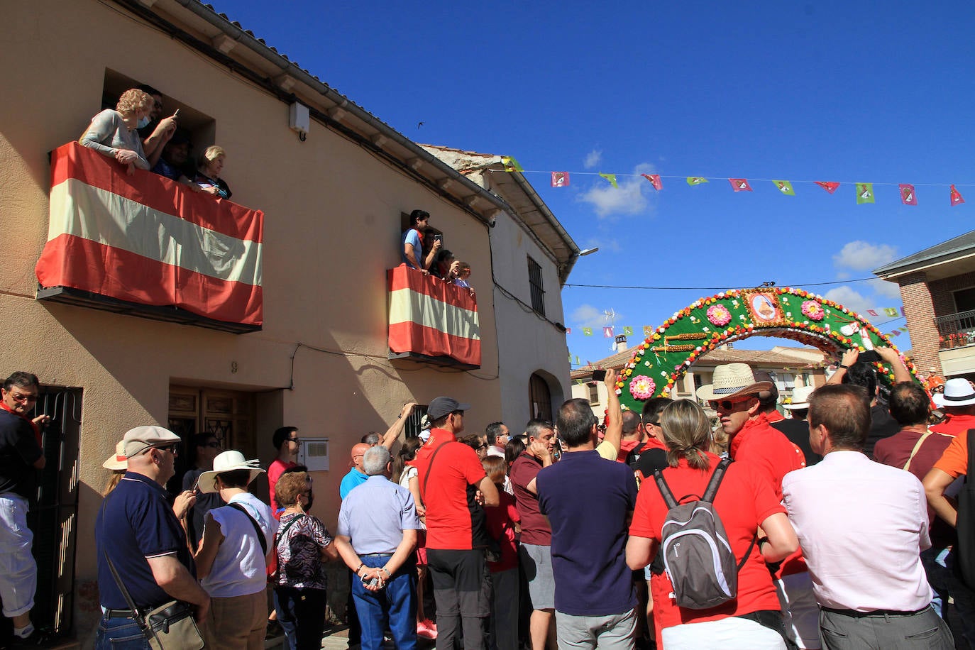 Los grupos de paloteo preceden el paso de la Virgen del Castillo por uno de los arcos de flores de papel en Bernardos. 