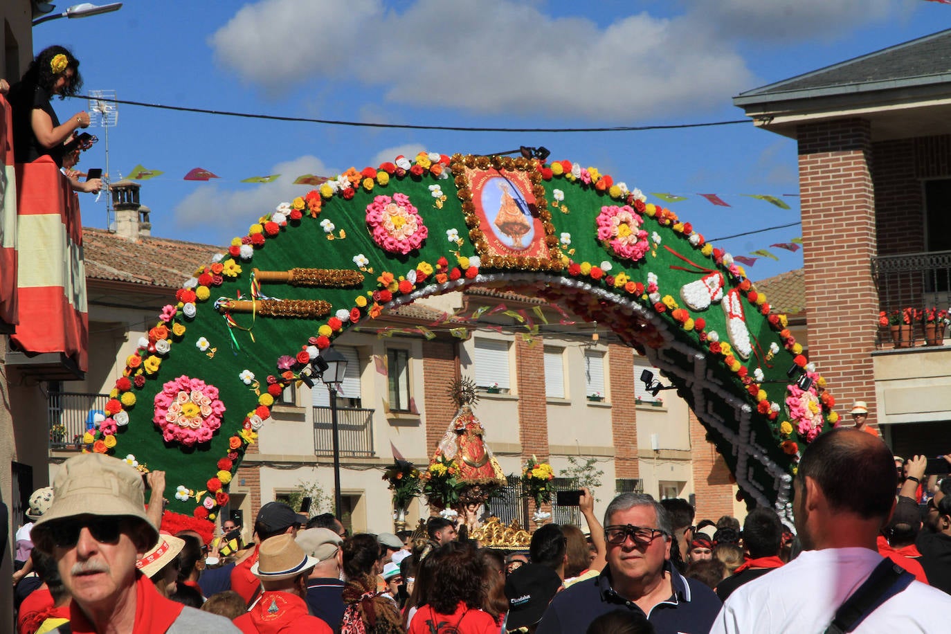 Los grupos de paloteo preceden el paso de la Virgen del Castillo por uno de los arcos de flores de papel en Bernardos. 