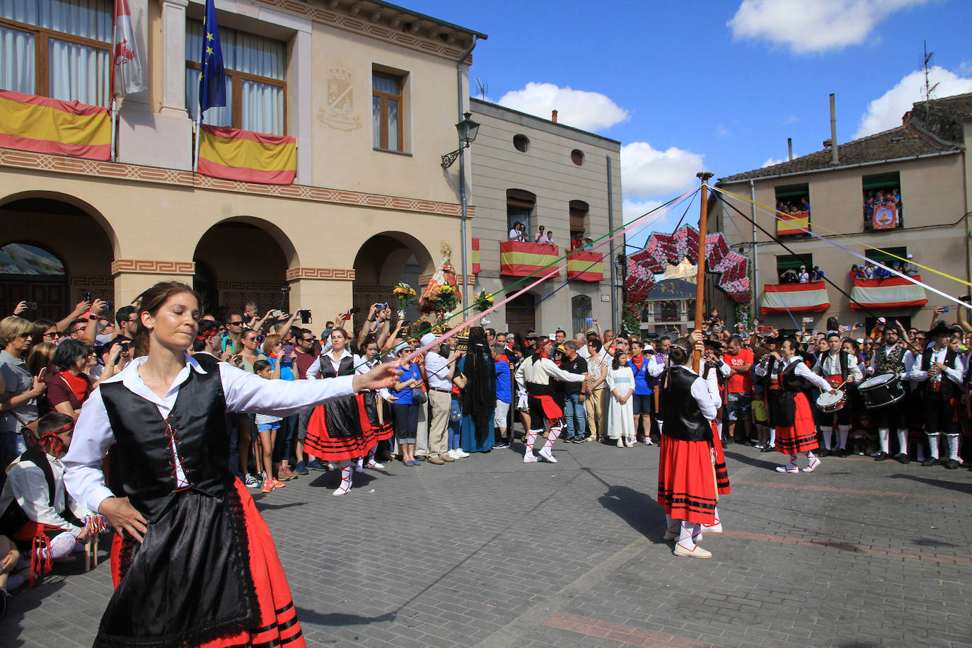 Los grupos de paloteo preceden el paso de la Virgen del Castillo por uno de los arcos de flores de papel en Bernardos. 