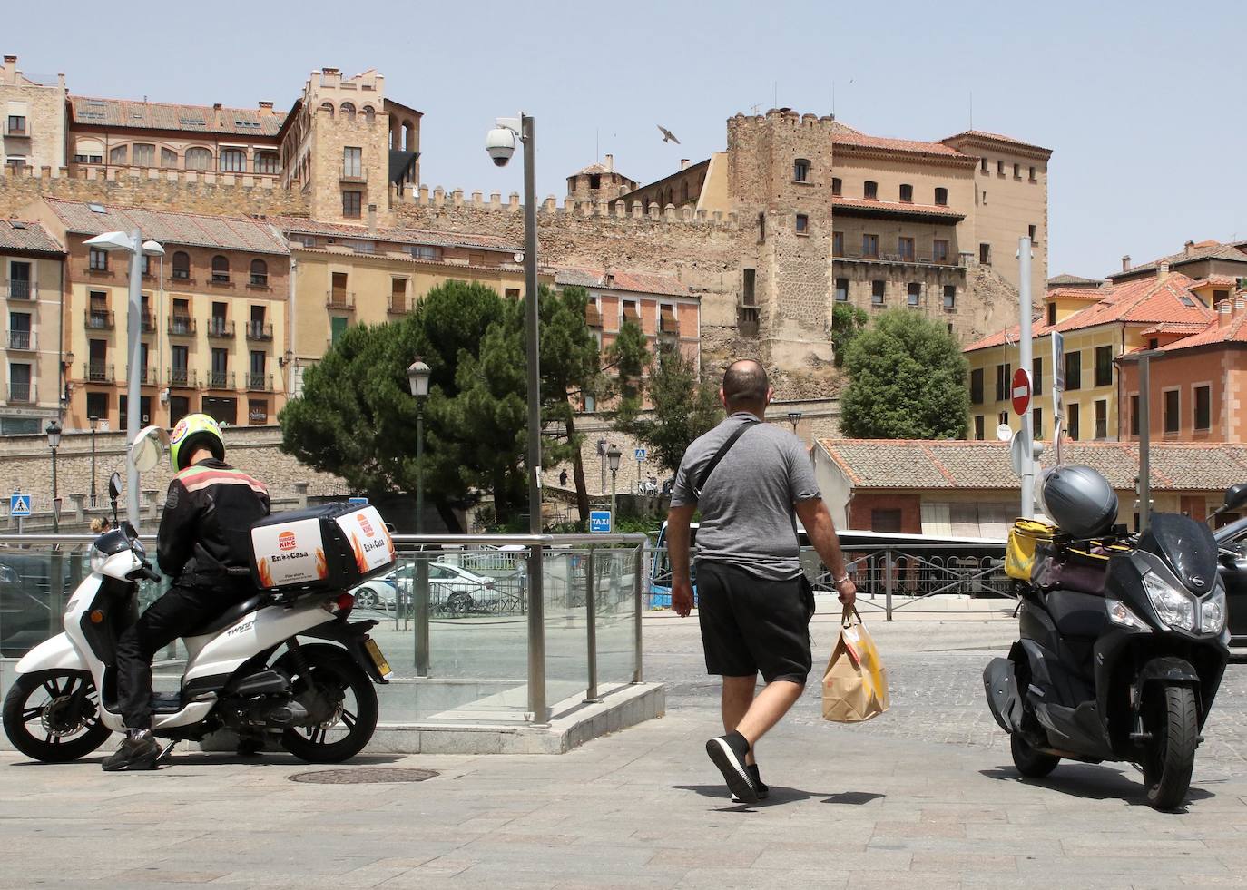 Un repartidor de comida a domicilio carga con un pedido en su motocicleta, parada en la avenida Padre Claret.