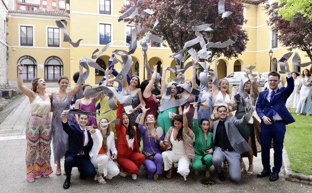 Algunos de los nuevos graduados lanzan sus bandas al cielo en los jardines del palacio.