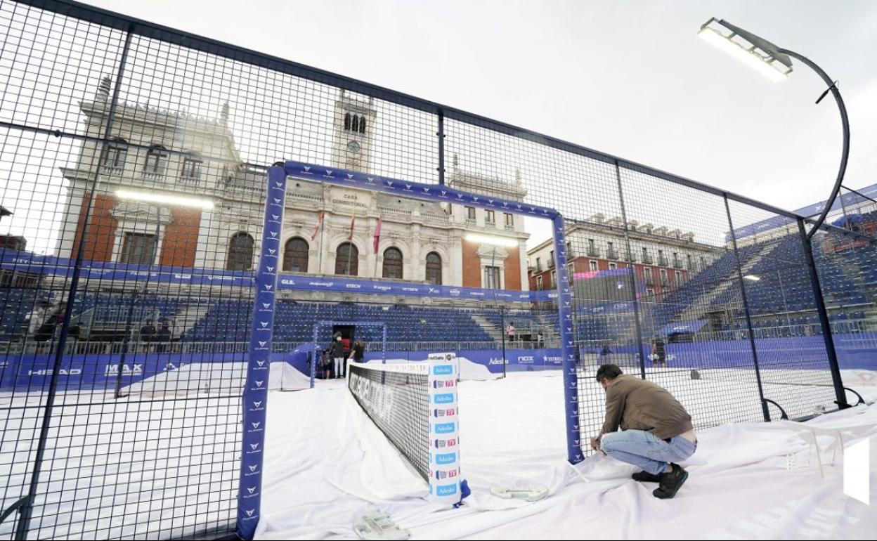 Un operario termina de cerrar la lona con la que se cubrió la pista central de la Plaza Mayor por la lluvia. 
