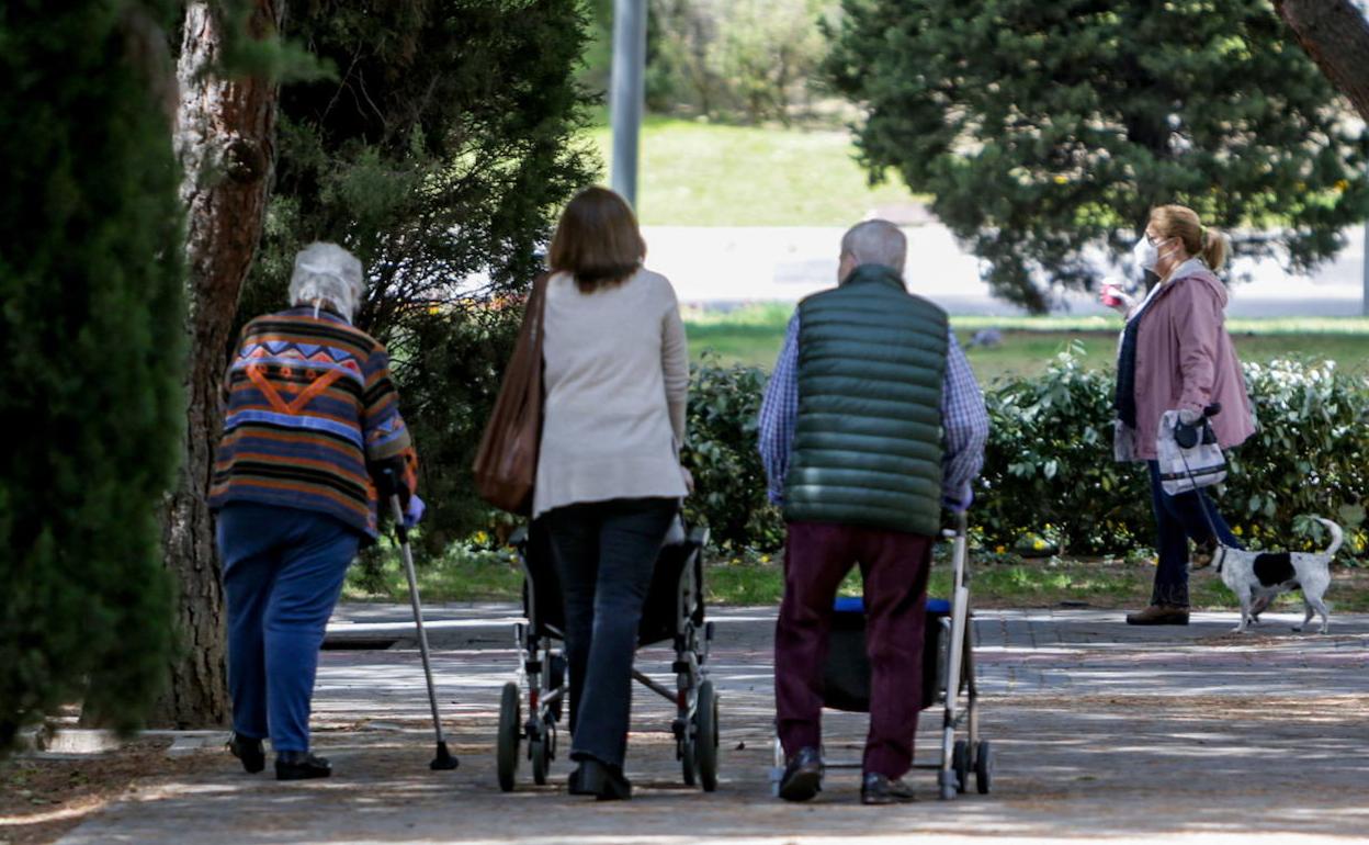 Personas mayores paseando por un parque.