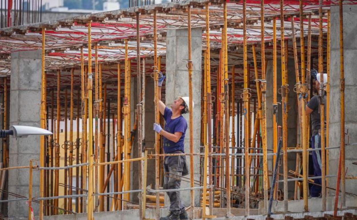 Dos obreros trabajan en la construcción de un edificio.