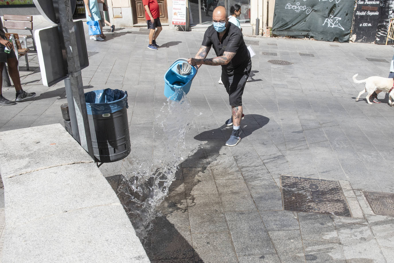 Un comerciante de la calle San Francisco limpia la suciedad en la acera. 