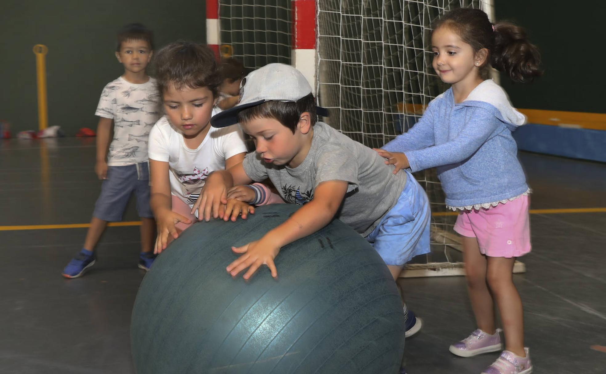 Un grupo de niños juega con una pelota gigante. 