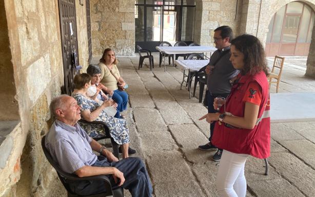 Imagen principal - El párroco de Monsagro y la psicóloga hablan con algunos de los vecinos; Hilario, aficionado a la pintura, enseña una de sus obras que tiene fotografiadas en el teléfono y otra vecina en la habitación que la han cedido. 