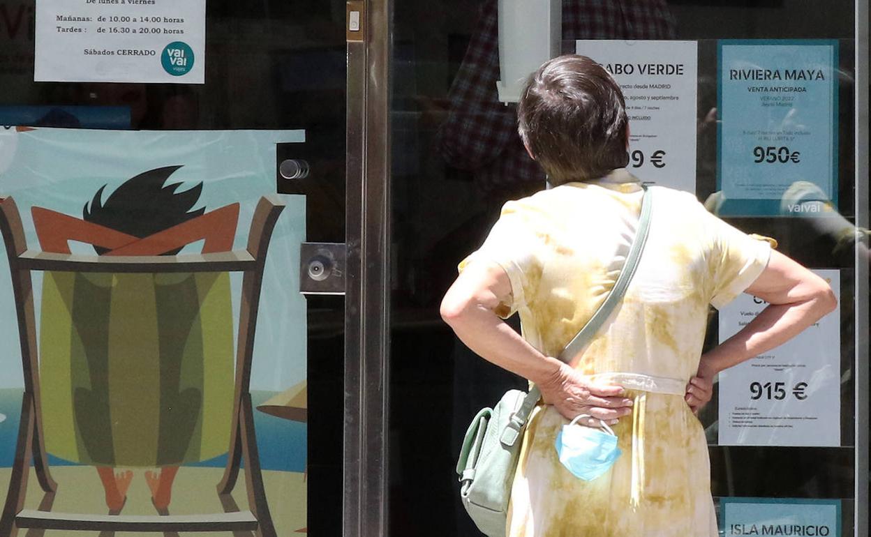 Una mujer observa los carteles anunciadores de viajes en el escaparate de una agencia de Segovia. 