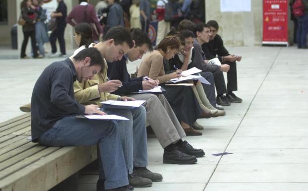 Un grupo de jóvenes rellena sus currículums en una feria de empleo para universitarios. 