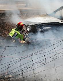 Imagen secundaria 2 - Los bomberos apagan el coche incendiado. 