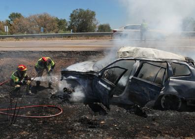 Imagen secundaria 1 - Los bomberos apagan el coche incendiado. 