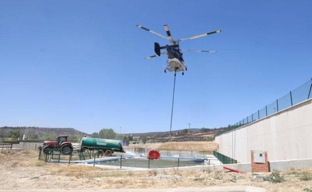 Helicóptero carga agua en una piscina de Silos, este lunes.