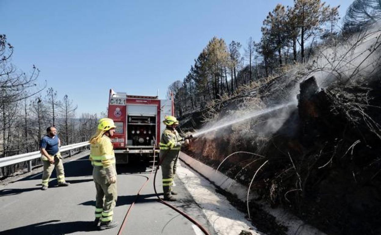 Los bomberos refrescan la zona para evitar que se reaviven las llamas. 