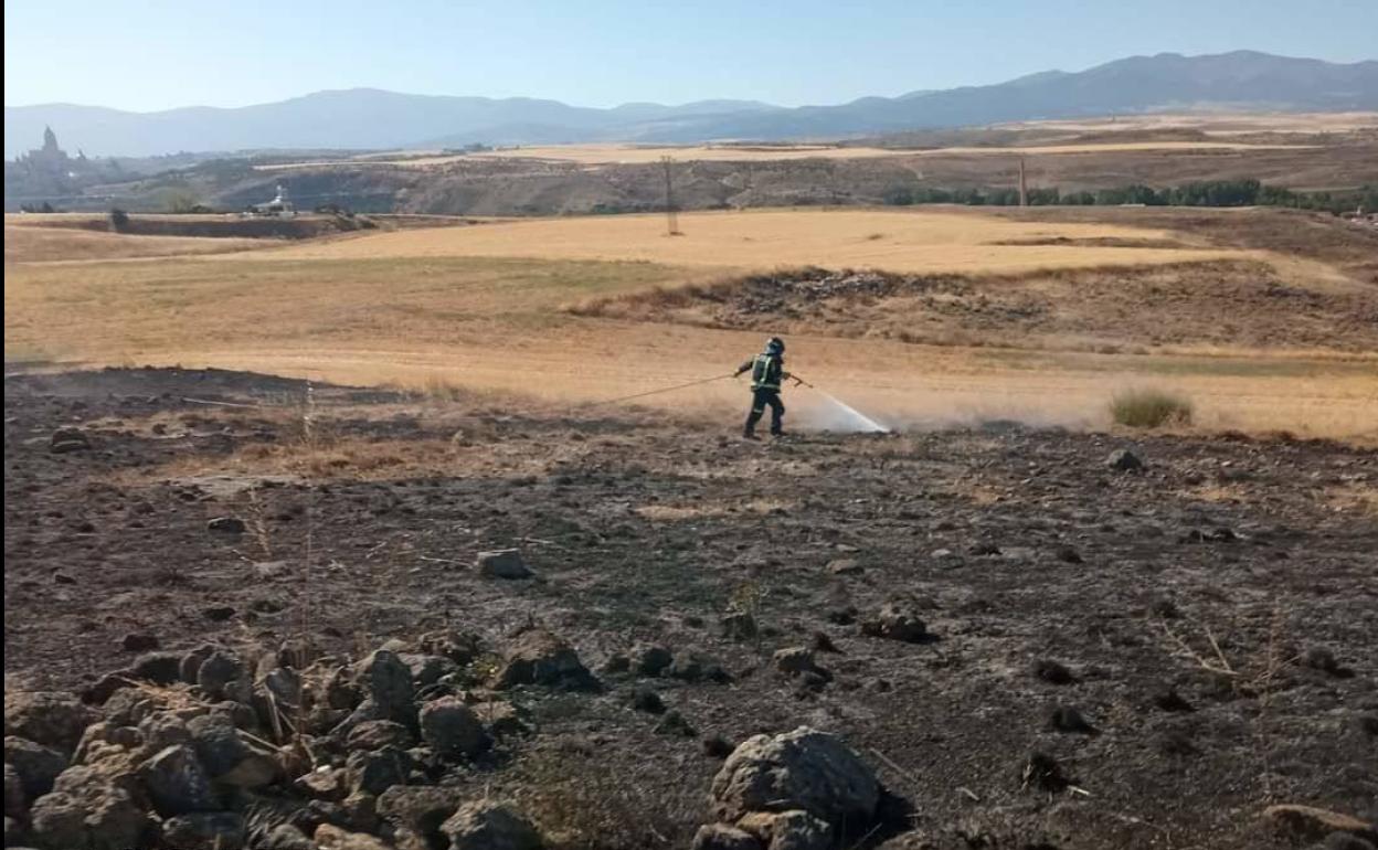 Un bombero de Segovia apaga con una manguera restos del fuego cerca del Peñigoso. 