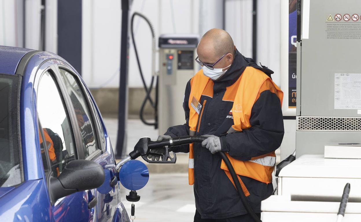 Operario de una gasolinera echando combustible a un coche. 